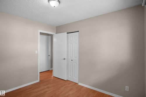 Interior room featuring wood-finish flooring, light beige wall paint, and white trim - 13524 26 Street, Edmonton, AB 