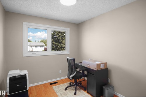 Neutral-toned interior room with wood-finish flooring, a white window frame, and a white ceiling - 13524 26 Street, Edmonton, AB 