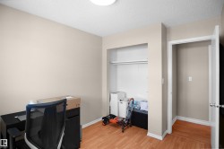 Neutral-toned room featuring wood-finish flooring, a built-in closet with shelving and hanging rod, and a doorway with white trim - 