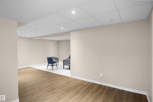 Expansive room featuring wood-finish flooring, light neutral wall paint, and recessed lighting - 13524 26 Street, Edmonton, AB 