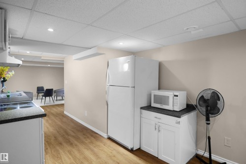 Kitchenette featuring wood-finish flooring, white cabinetry, and a dark countertop - 13524 26 Street, Edmonton, AB 