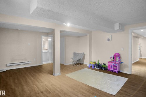 Spacious room featuring wood-finish flooring, light neutral wall paint, and recessed lighting - 13524 26 Street, Edmonton, AB 