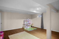 Spacious room featuring wood-finish flooring, a neutral wall color, and a window for natural light - 
