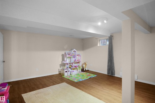 Spacious room featuring wood-finish flooring, a neutral wall color, and a window for natural light - 13524 26 Street, Edmonton, AB 