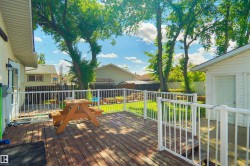 Expansive wood deck featuring white railings and direct access to a grassy yard - 