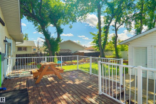 Expansive wood deck featuring white railings and direct access to a grassy yard - 13524 26 Street, Edmonton, AB 