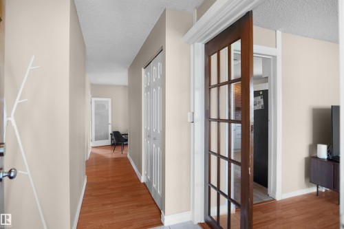 Warm wood-finish flooring extending through an interior hallway - 13524 26 Street, Edmonton, AB 