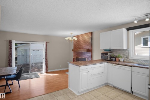 Modern kitchen featuring white cabinetry, a mosaic tile backsplash, and a built-in dishwasher - 13524 26 Street, Edmonton, AB 