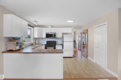 Well-appointed kitchen featuring white cabinetry, a mosaic tile backsplash, a built-in microwave, and a breakfast bar - 