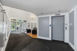 Lobby area featuring dual glass entry doors with a decorative transom, a prominent chandelier, recessed lighting, and a passenger elevator - 
