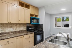 Kitchen featuring light wood-finish cabinetry, patterned tile backsplash, and dark patterned countertops - 