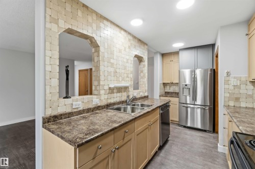 Kitchen featuring light wood cabinetry, stone-look countertops, stainless steel appliances, a double basin sink, and recessed lighting - 121 5125 Riverbend Road Nw, Edmonton, AB 
