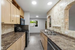 Kitchen with light wood-finish cabinetry, dark speckled countertops, and a full tile backsplash - 