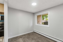 Bright room with wood-finish flooring, featuring a large window, white trim, and a ceiling-mounted light fixture - 