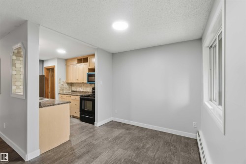 Open-concept living space featuring wood-finish flooring, a contemporary window, and a recessed ceiling light - 121 5125 Riverbend Road Nw, Edmonton, AB 