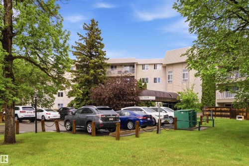 Multi-story building exterior featuring a neutral-toned facade, multiple balconies with white railings, and a covered entrance - 121 5125 Riverbend Road Nw, Edmonton, AB 