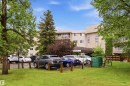 Multi-story building exterior featuring a neutral-toned facade, multiple balconies with white railings, and a covered entrance - 121 5125 Riverbend Road Nw, Edmonton, AB 