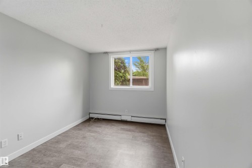 Neutral wall paint, wood-finish flooring, white trim, and a window with a white frame - 121 5125 Riverbend Road Nw, Edmonton, AB 
