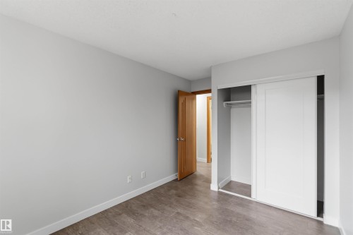 Light gray wall paint with white baseboards, wood-finish flooring, and a white sliding closet door - 121 5125 Riverbend Road Nw, Edmonton, AB 