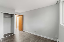 Room featuring wood-finish flooring, light gray walls, white trim, and a window with a curtain rod - 