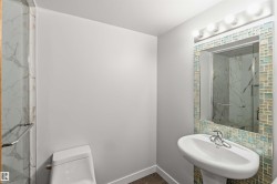 Modern bathroom featuring a tiled mirror frame, pedestal sink, and glass-enclosed shower with marble-look tile - 
