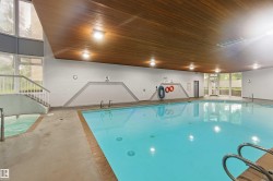 Indoor swimming pool featuring a wood-finish ceiling, integrated lighting, and a separate spa - 