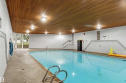 Indoor swimming pool featuring a wood-finish ceiling, perimeter lighting, and large windows - 