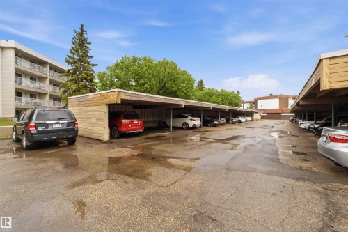 Covered parking structures featuring wood-look siding and a flat roofline - 121 5125 Riverbend Road Nw, Edmonton, AB 