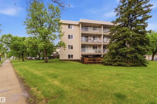 Four-story building with beige siding and multiple private balconies featuring white railings - 121 5125 Riverbend Road Nw, Edmonton, AB 
