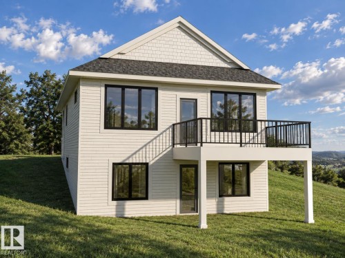 Two-story exterior with white horizontal siding and shingle accents, featuring a black-railed deck, multiple black-framed windows, and a black shingled roof - 11 Brickyard View, Stony Plain, AB 