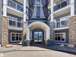Building entrance featuring an arched portico, stone-clad columns, and a glass-paneled double door - 