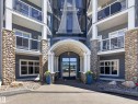 Building entrance featuring an arched portico, stone-clad columns, and a glass-paneled double door - 138 16035 132 Street, Edmonton, AB 