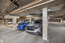 Dedicated parking space with concrete structural elements, exposed utility lines, and overhead lighting - 