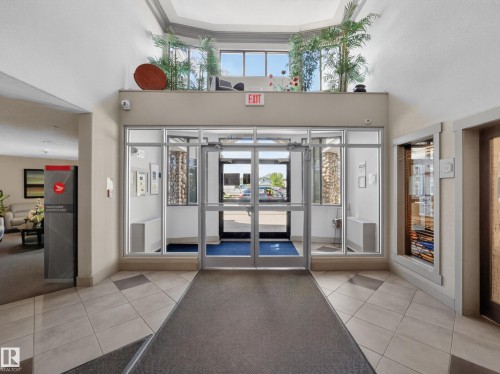 Foyer entrance featuring glass doors, tiled flooring, high ceilings, and an upper window shelf with decorative plants - 138 16035 132 Street, Edmonton, AB 