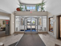 Foyer entrance featuring glass doors, tiled flooring, high ceilings, and an upper window shelf with decorative plants - 