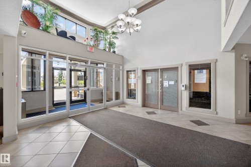 Spacious foyer featuring high ceilings, a contemporary multi-light chandelier, and large format floor tile - 138 16035 132 Street, Edmonton, AB 