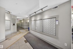 Corridor featuring an array of individual mailboxes, recessed ceiling lighting, track lighting, and wall-mounted sconces - 