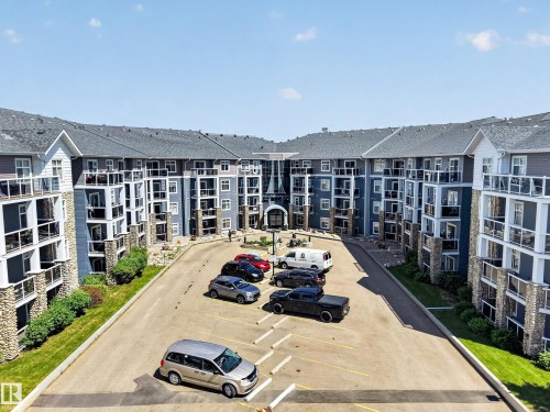 Contemporary apartment building with blue siding and stone accents, featuring multiple private balconies with glass railings - 138 16035 132 Street, Edmonton, AB 