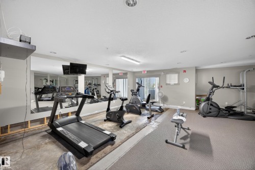 Fitness area featuring wall-mounted mirrors, recessed lighting, and sliding glass doors - 138 16035 132 Street, Edmonton, AB 