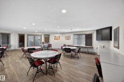 Spacious common area featuring wood-finish flooring, recessed lighting, and multiple windows with blinds - 