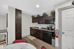 Kitchenette featuring dark wood-finish cabinetry, a single basin sink, and wood-finish flooring - 