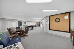 Spacious recreational room featuring gray patterned carpeting, recessed lighting, and a dartboard with a cork surround - 