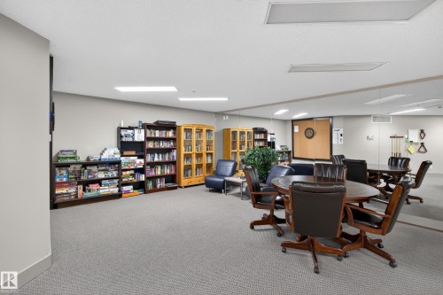 Recreation room featuring carpeted flooring, recessed lighting, built-in shelving, a mirrored wall, and a dartboard - 138 16035 132 Street, Edmonton, AB 