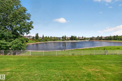Expansive green lawn with a chain-link fence bordering a large body of water - 138 16035 132 Street, Edmonton, AB 