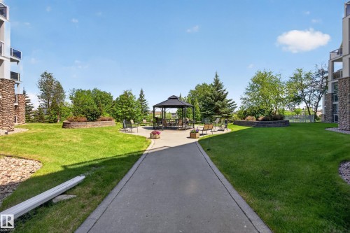 Landscaped courtyard featuring a central gazebo, paved pathways, and manicured green spaces - 138 16035 132 Street, Edmonton, AB 