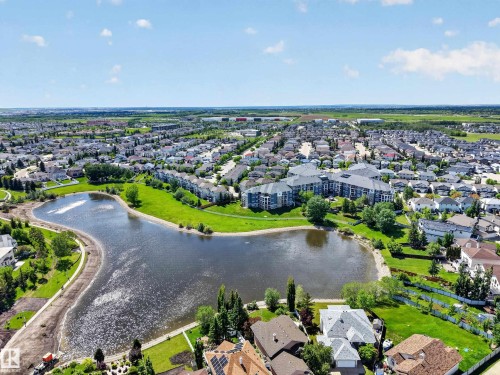 Expansive residential area featuring a central lake surrounded by green spaces and mature landscaping - 138 16035 132 Street, Edmonton, AB 