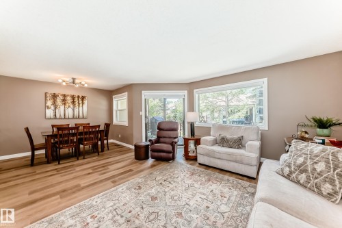 Open-concept living and dining area featuring wood-finish flooring, neutral wall tones, and recessed lighting - 10822 11 Avenue, Edmonton, AB 