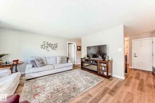Open-concept living area featuring wood-finish flooring, light neutral wall tones, and white trim - 10822 11 Avenue, Edmonton, AB 