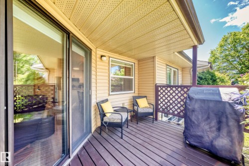 Expansive outdoor deck featuring wood-finish decking, a sliding glass door with screen, and a lattice privacy screen - 10822 11 Avenue, Edmonton, AB 