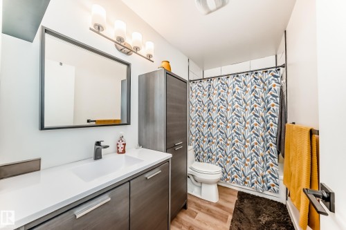 Modern bathroom featuring a wood-finish vanity with a white countertop and integrated sink - 10822 11 Avenue, Edmonton, AB 